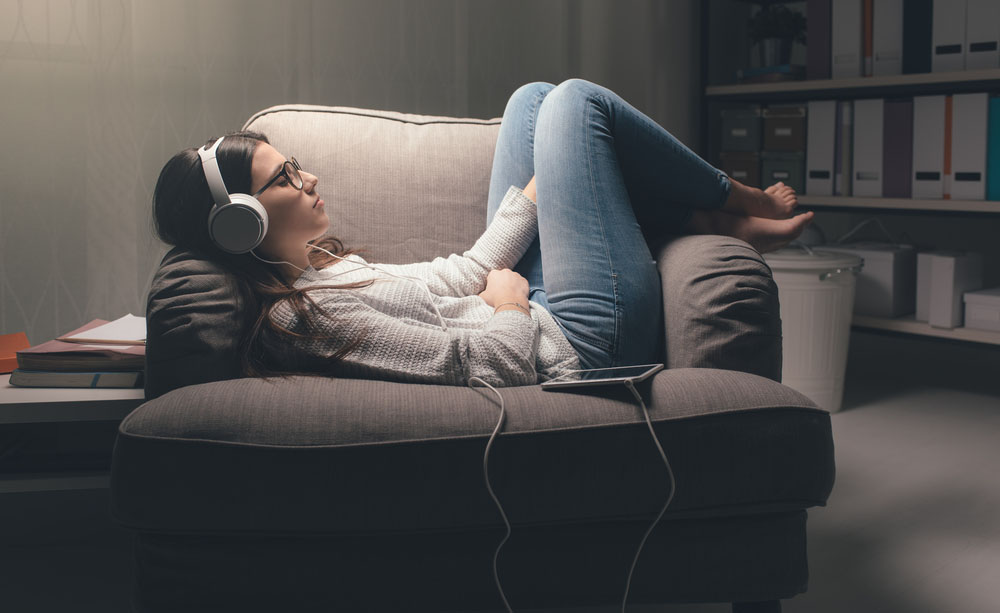 Una joven escucha un audiolibro en un sillón