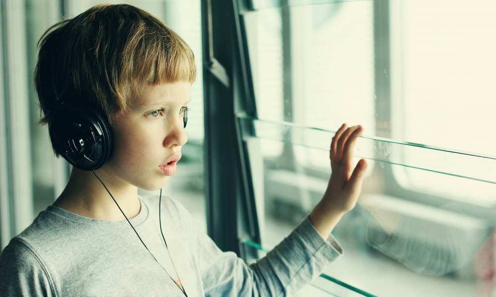 Un niño mira por una ventana con unos auriculares puestos