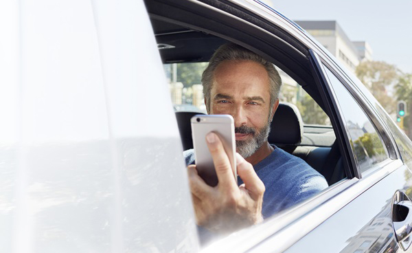 Un hombre utiliza su smartphone dentro de un coche
