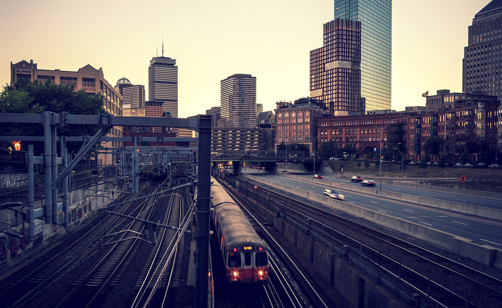 Fotografía panorámica de Boston al atardecer con un tren en primer plano