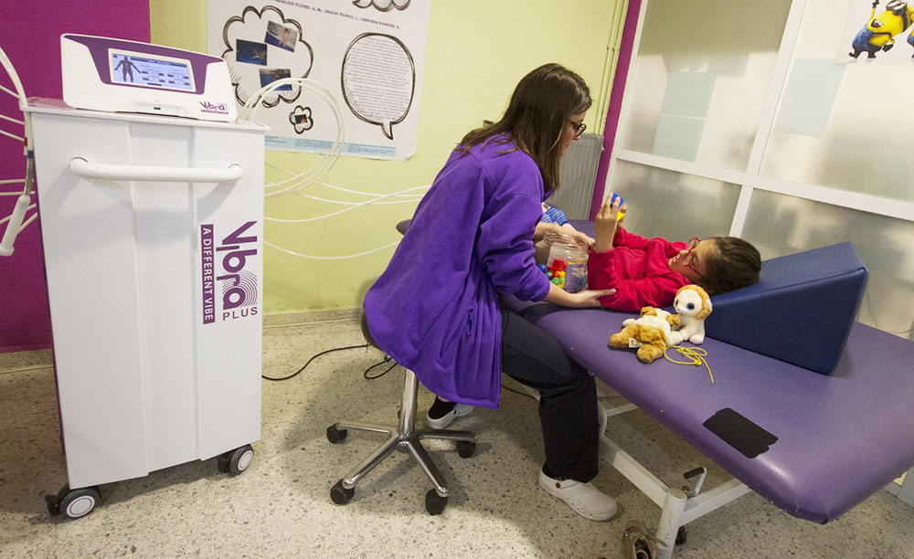 Una niña con parálisis cerebral participa en la Terapia Vibra junto a un especialista