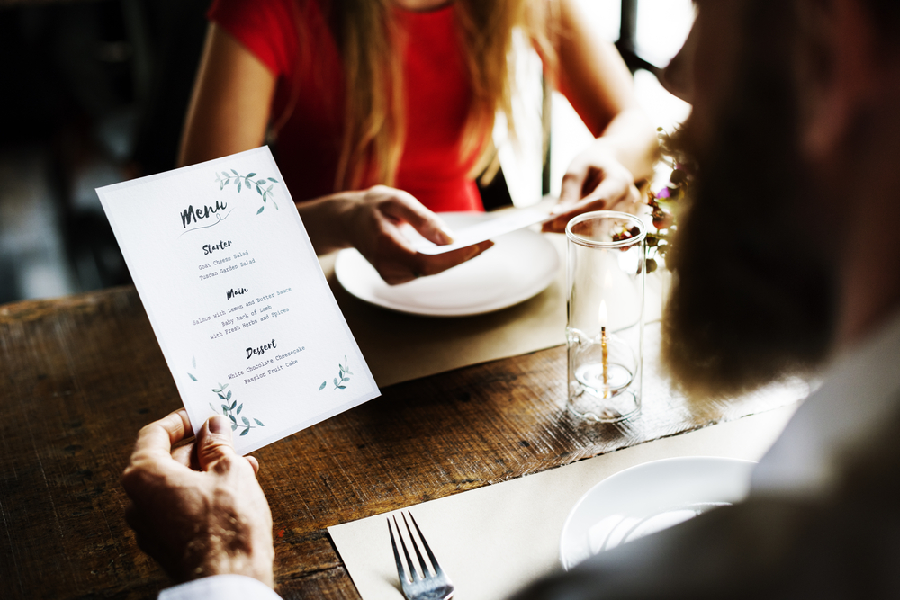 Una pareja de hombre y mujer ven una carta en un restaurante