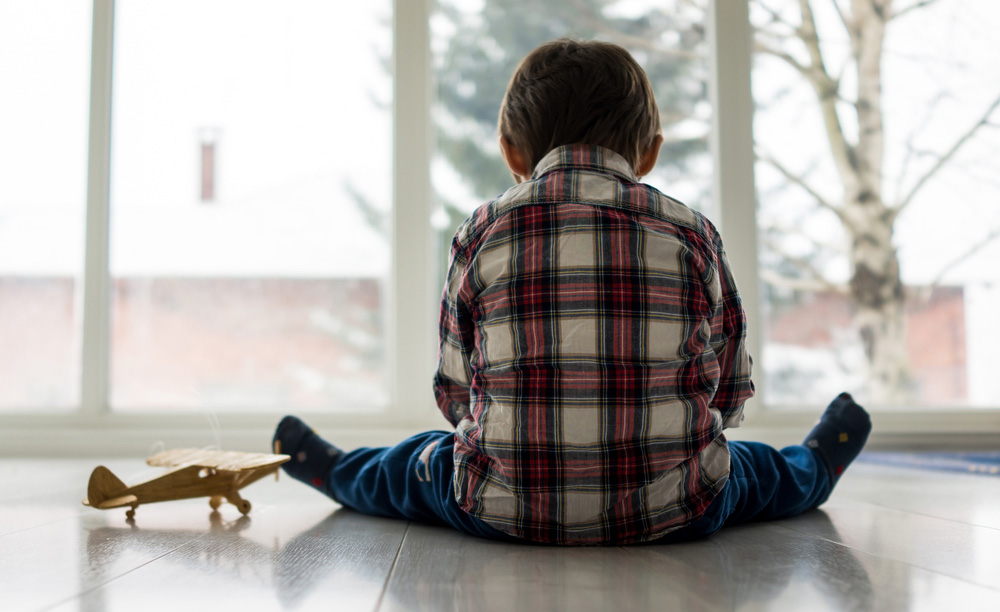Fotografía de un niño con TEA sentado frente a una ventana