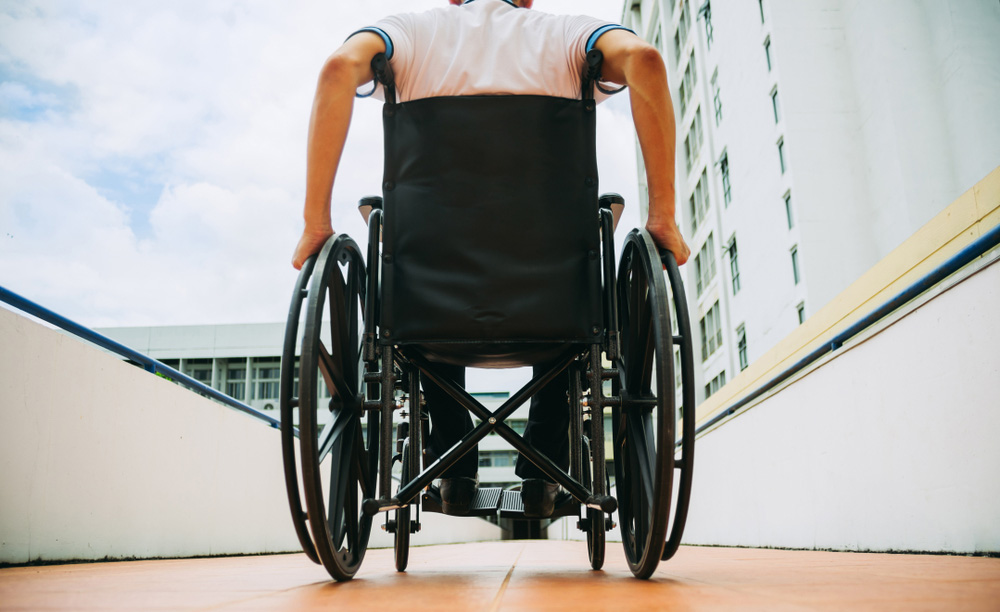 Una persona en silla de ruedas sube una rampa en el exterior de unos edificios