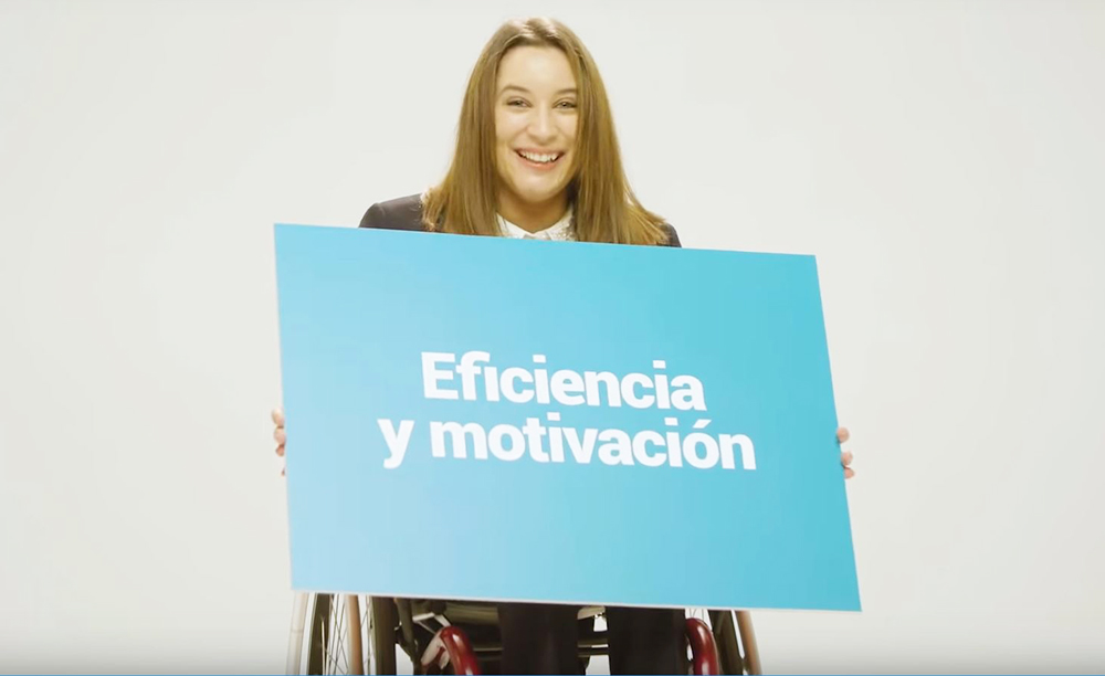 Fotograma del v&iacute;deo elaborado por Cocemfe que muestra a una mujer en silla de ruedas con un cartel