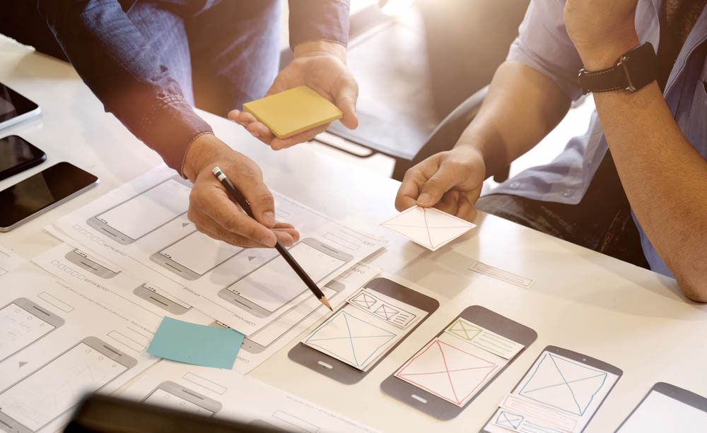 Varias personas trabajan en el dise&ntilde;o de una app para tel&eacute;fono m&oacute;vil