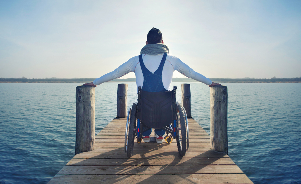Una persona en silla de ruedas en un muelle de un lago