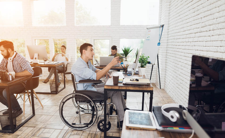 Un joven en silla de ruedas trabaja en una oficina