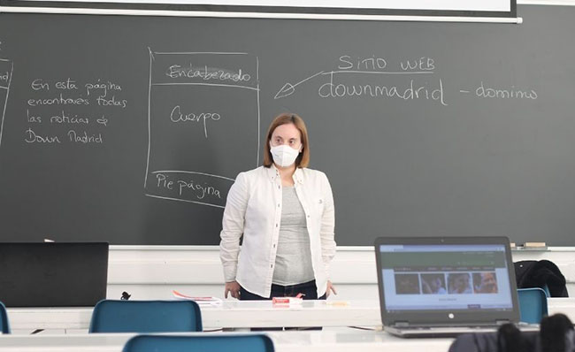 Fotografía del aula donde se imparte el curso sobre Tecnología de la Información y la Comunicación con una participante delante de la pizarra