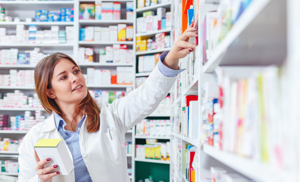 Una farmacéutica alcanza un medicamento en una estantería