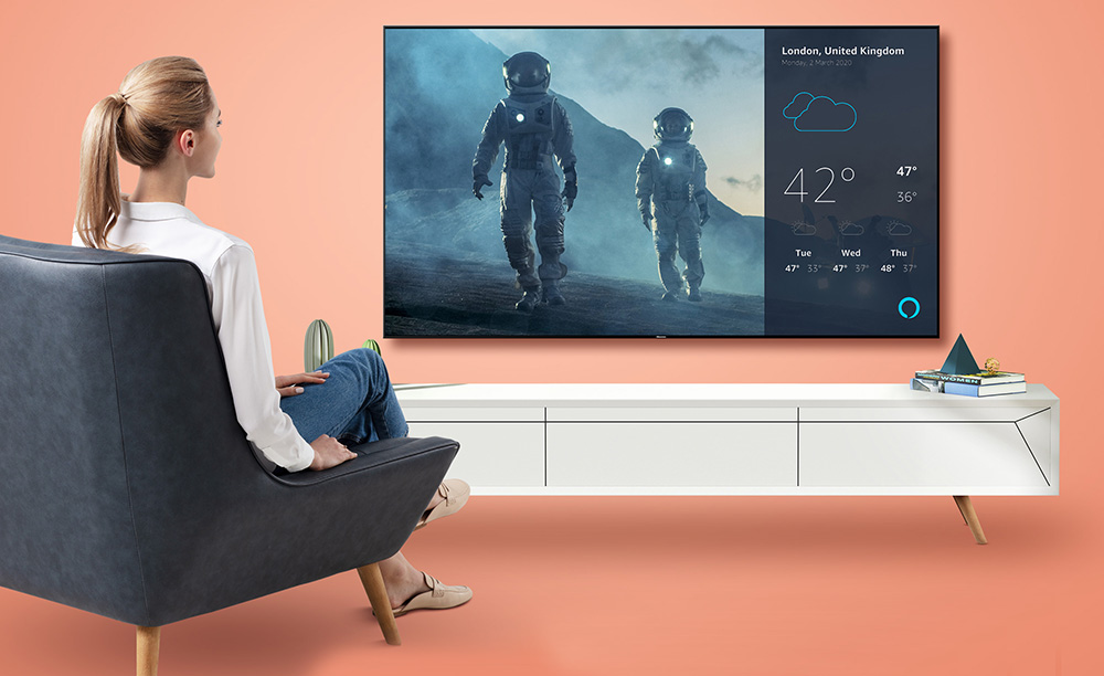 Foto comercial de una mujer viendo un televisor Hisense y utilizando Alexa