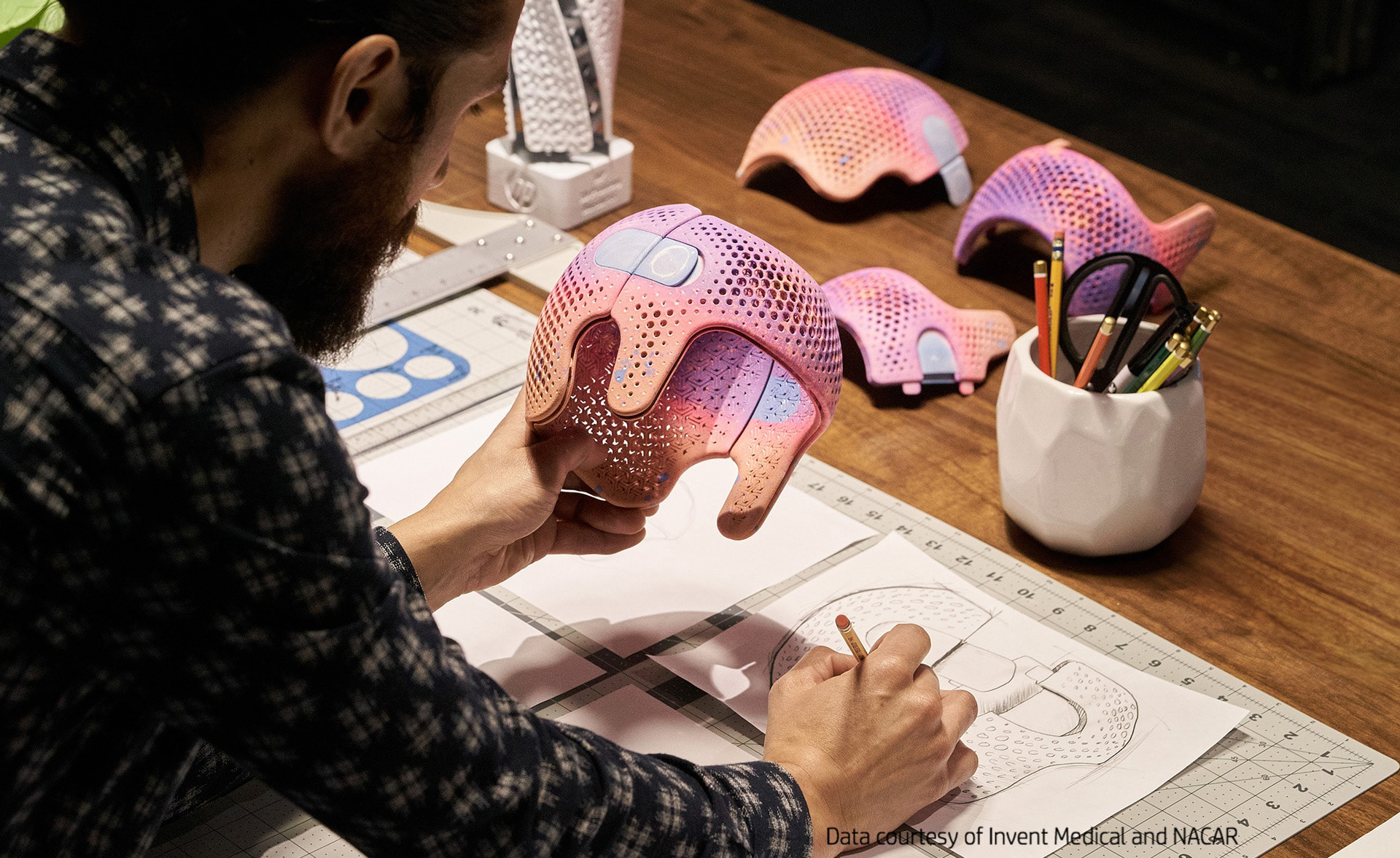 Un diseñador dibuja mientras sujeta en su mano un casco de niño realizado con impresora 3D