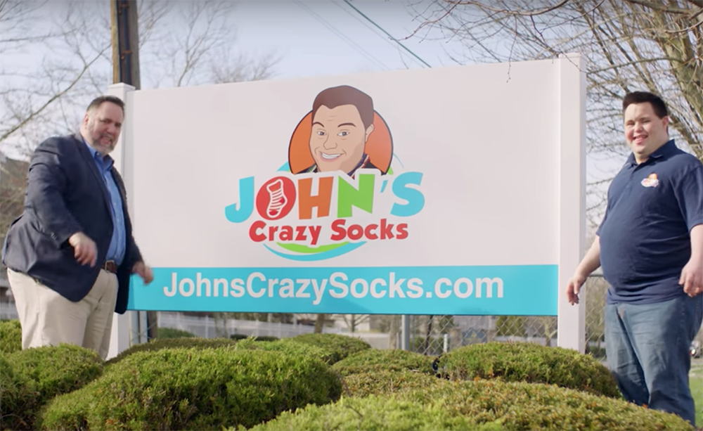 John y Mark Cronin frente al cartel de su empresa de calcetines