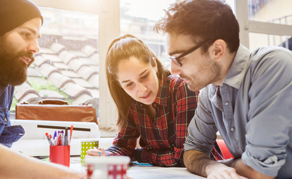 Varios j&oacute;venes sobre una mesa de trabajo