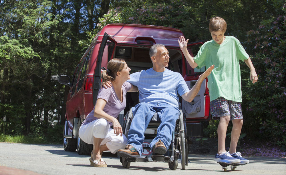 Un hombre en silla de ruedas por una lesión en la médula espinal junto a su mujer y su hijo
