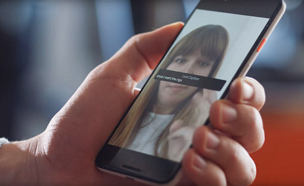 Una mano sostiene un móvil con una videollamada utilizando Live Captions