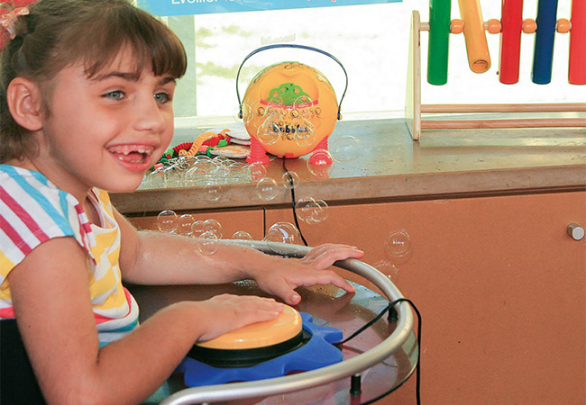 Una niña con discapacidad juega con la máquina de burbujas