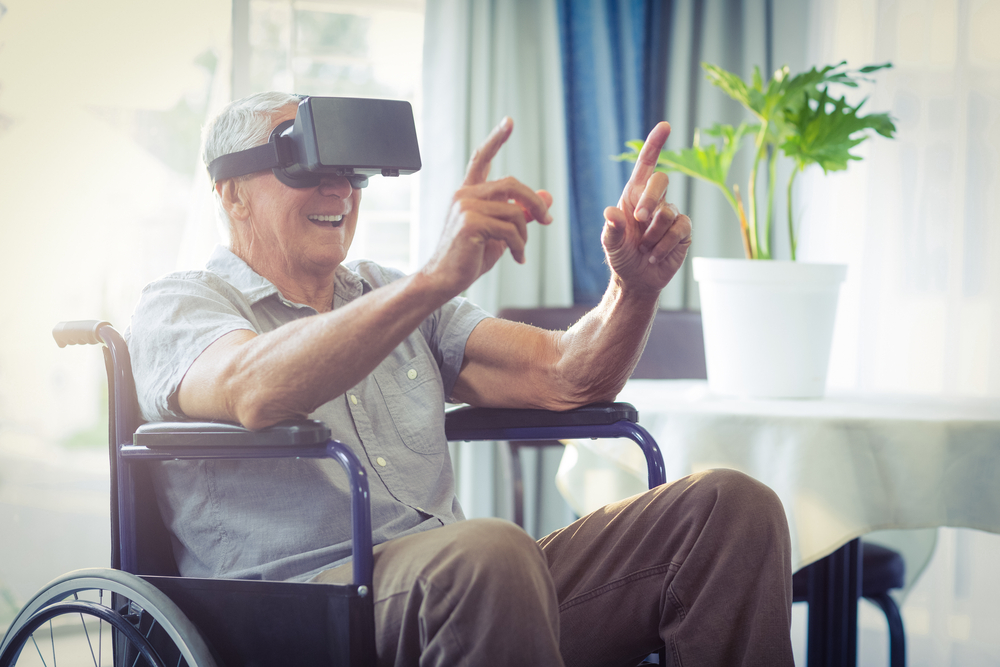 Una persona mayor en silla de ruedas utiliza unas gafas de realidad virtual