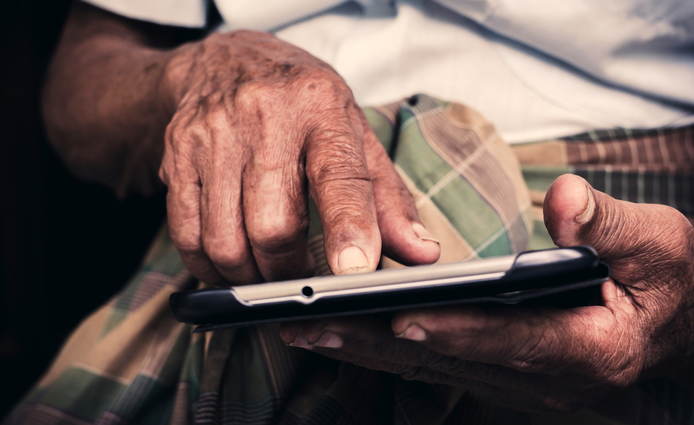 Una persona mayor utiliza una tableta con sus manos