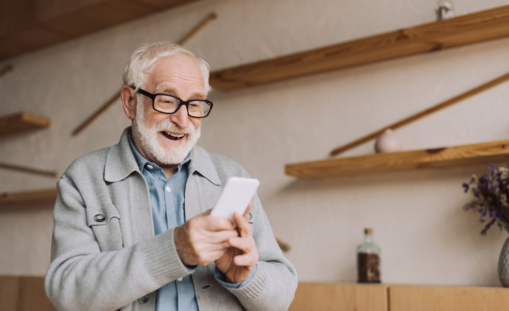 Un hombre mayor utiliza sonriente su teléfono móvil