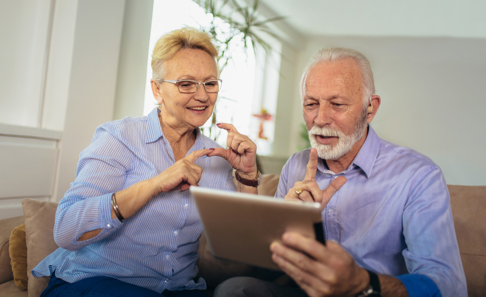 Una pareja de personas mayores habla con lengua de signos utilizando una tableta