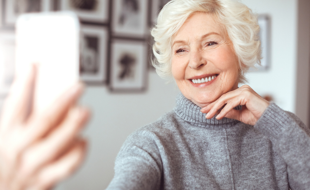 Una mujer mayor utiliza un teléfono móvil en su casa