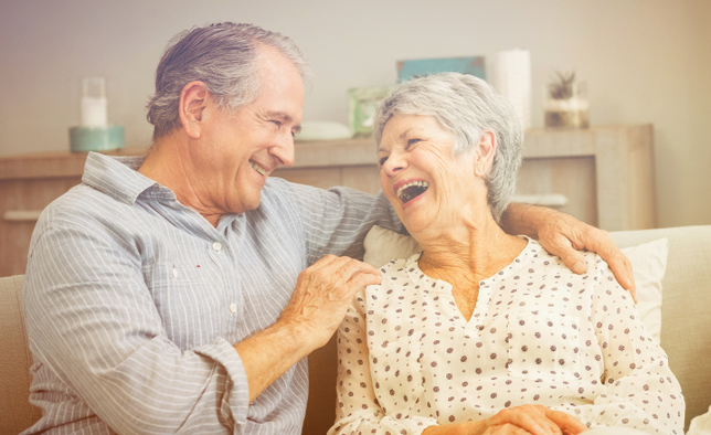 Una pareja de personas mayores riéndose en su hogar