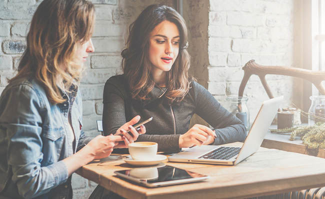 Dos mujeres hablan con un m&oacute;vil en la mano mientras trabajan