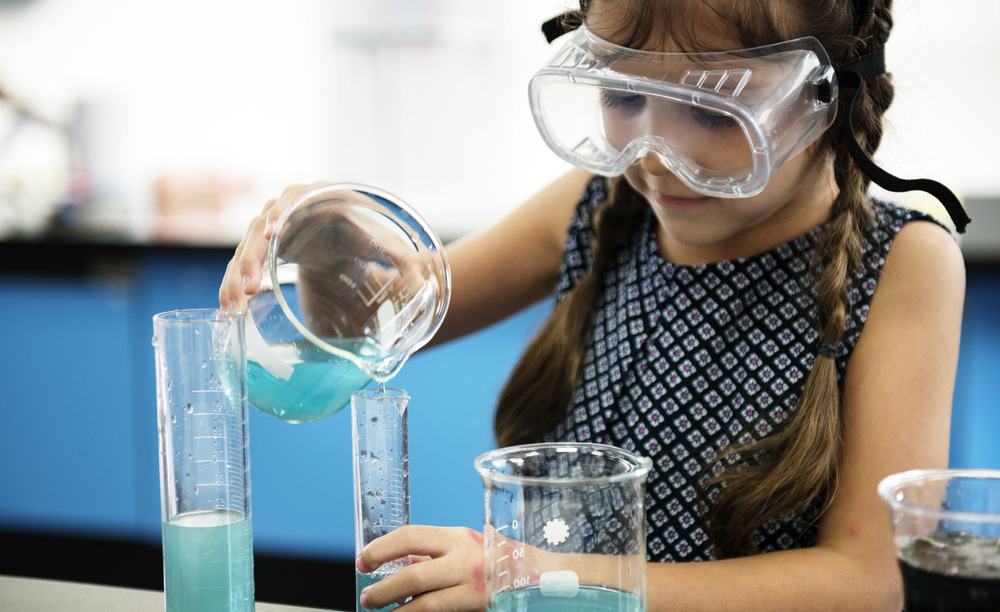 Una niña realiza un experimento con varios tubos con un líquido azul