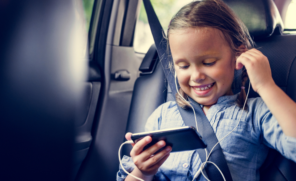 Una niña utiliza un teléfono móvil dentro de un coche