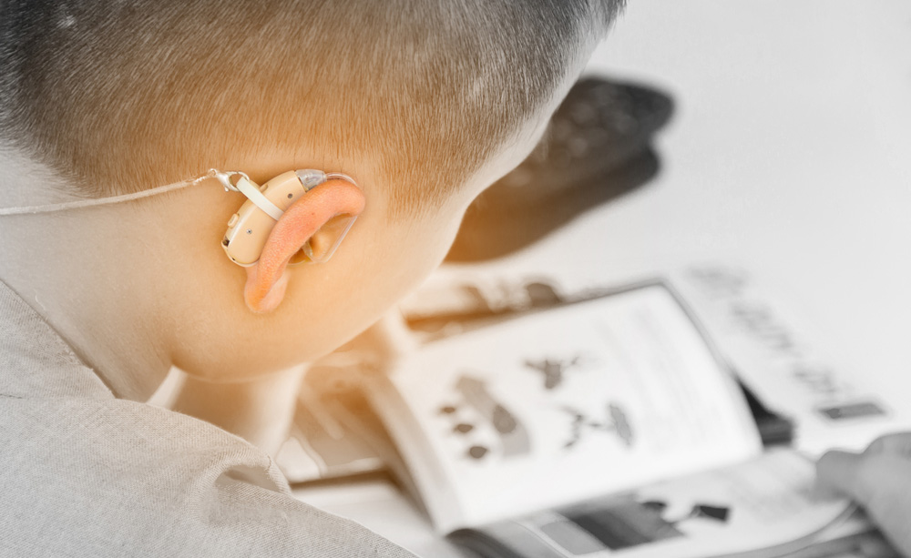 Un niño con discapacidad auditiva utiliza un audífono en el colegio