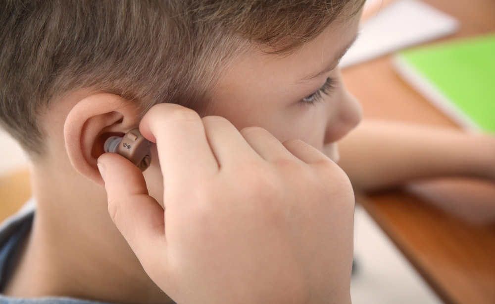 Un niño se coloca un audífono en la escuela