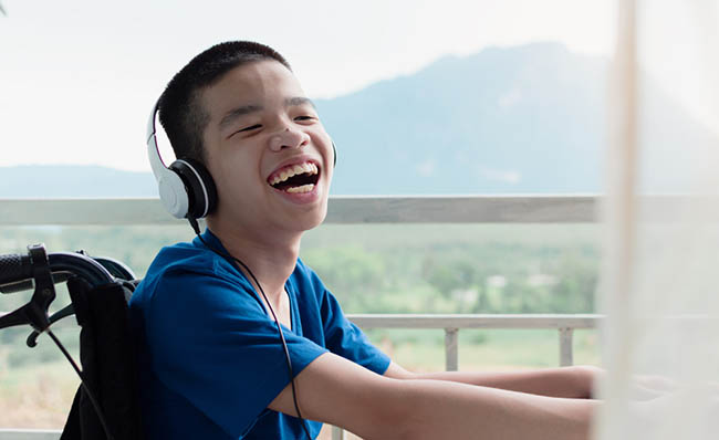 Un niño con discapacidad física ríe utilizando un portátil