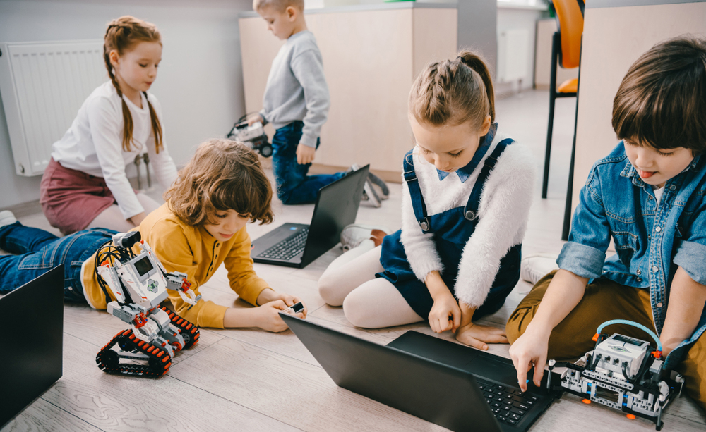 Varios ni&ntilde;os programan juntos entre varios ordenadores y robots