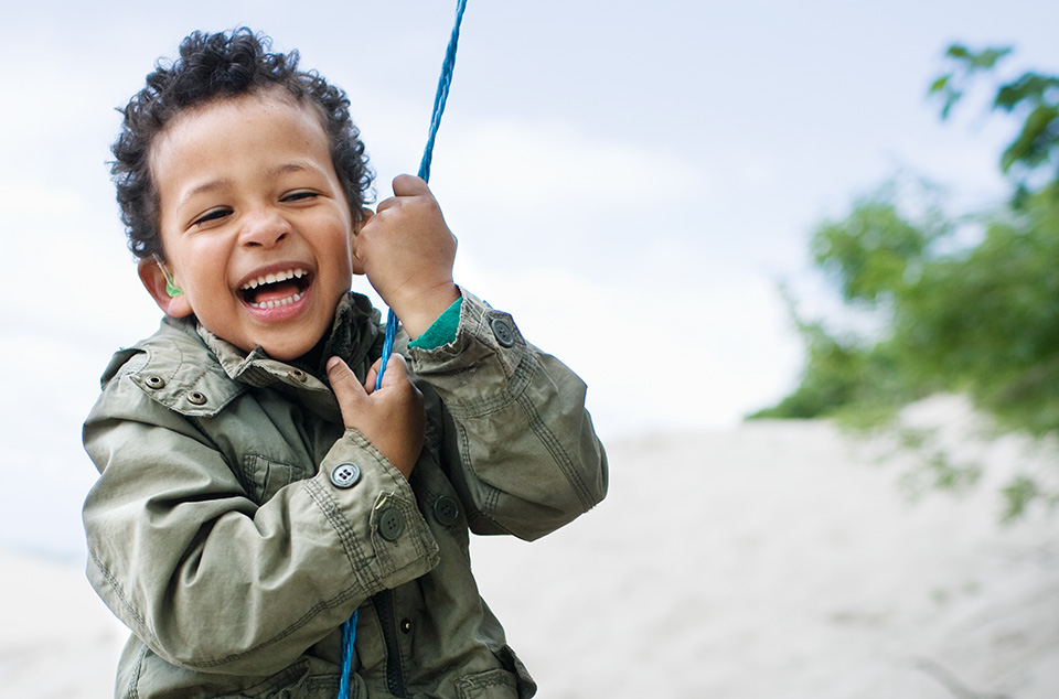 Un niño que utiliza audífono juega con una cuerda azul