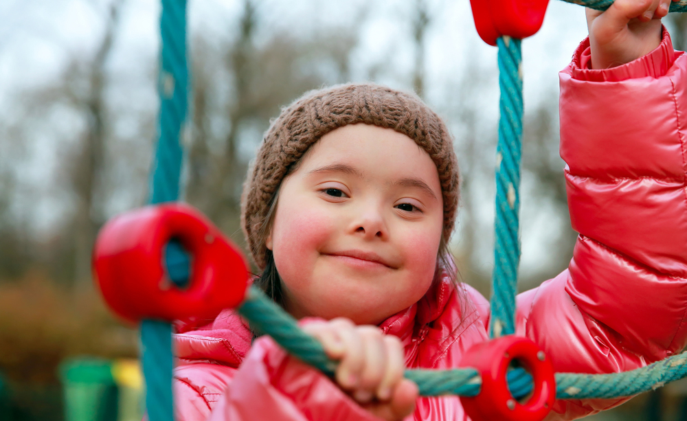 Una niña con síndrome de Down juega en un parque infantil