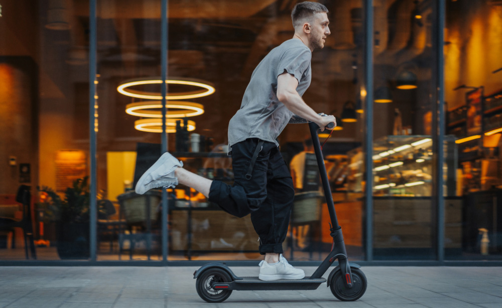 Un hombre utiliza un patinete el&eacute;ctrico por una acera