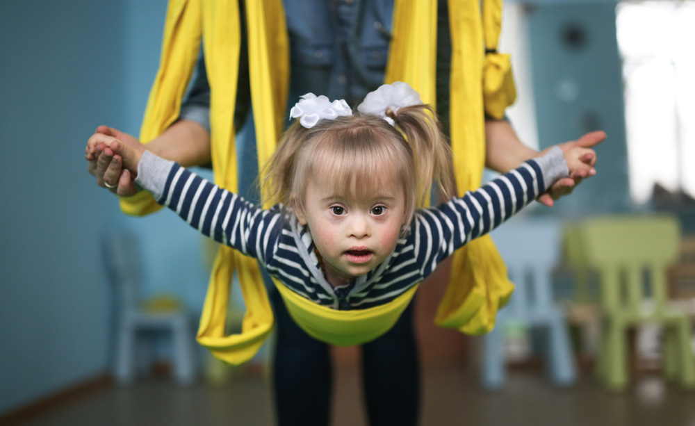 Una niña con síndrome de Down es suspendida en el aire mediante unas cintas