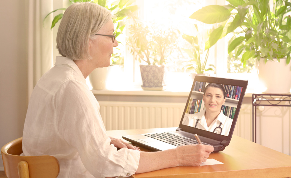 Una mujer mayor contacta a distancia con su médico utilizando un ordenador portátil