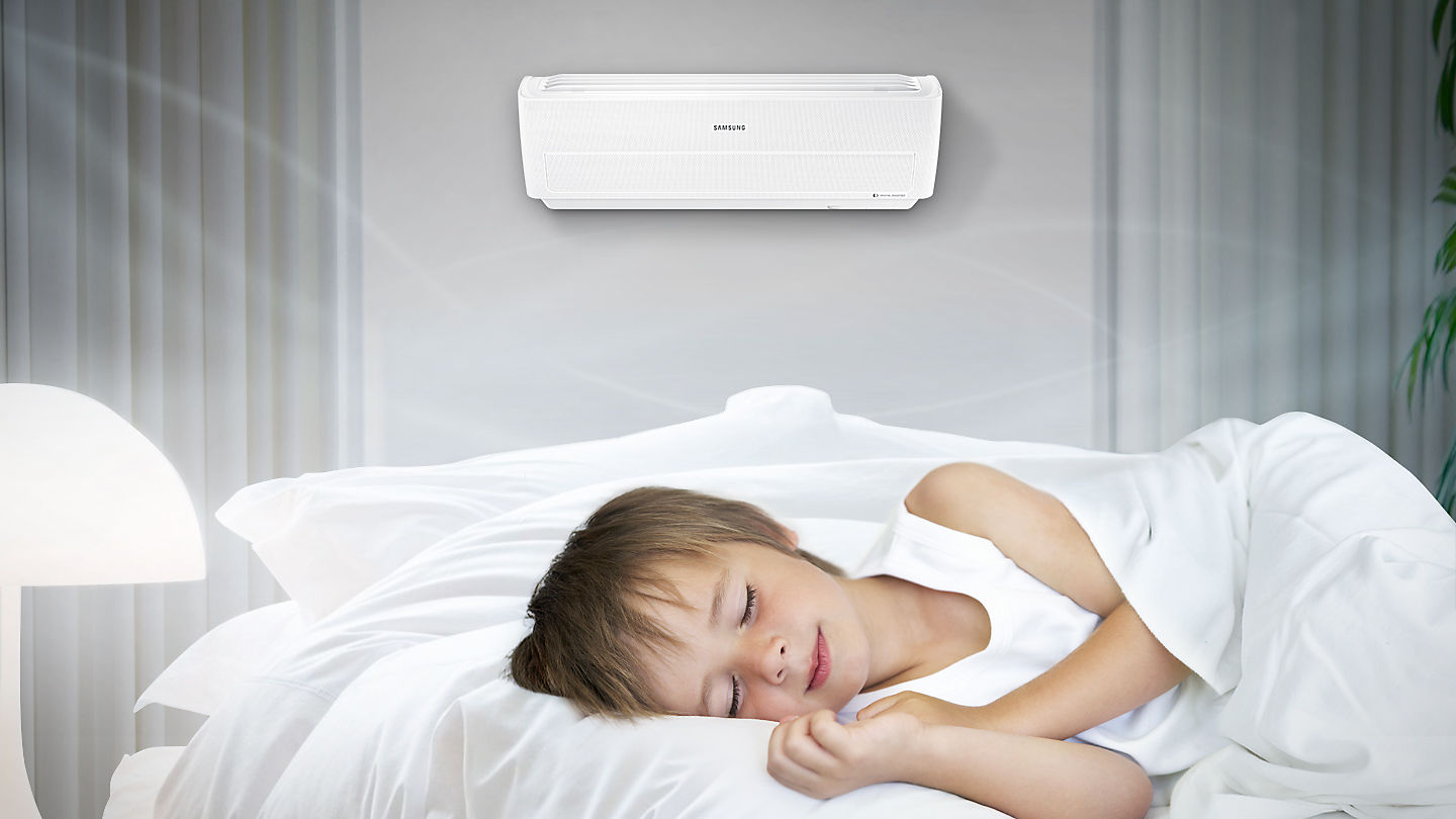 Un niño duerme en una habitación con una unidad de aire acondicionado Wind Free de Samsung