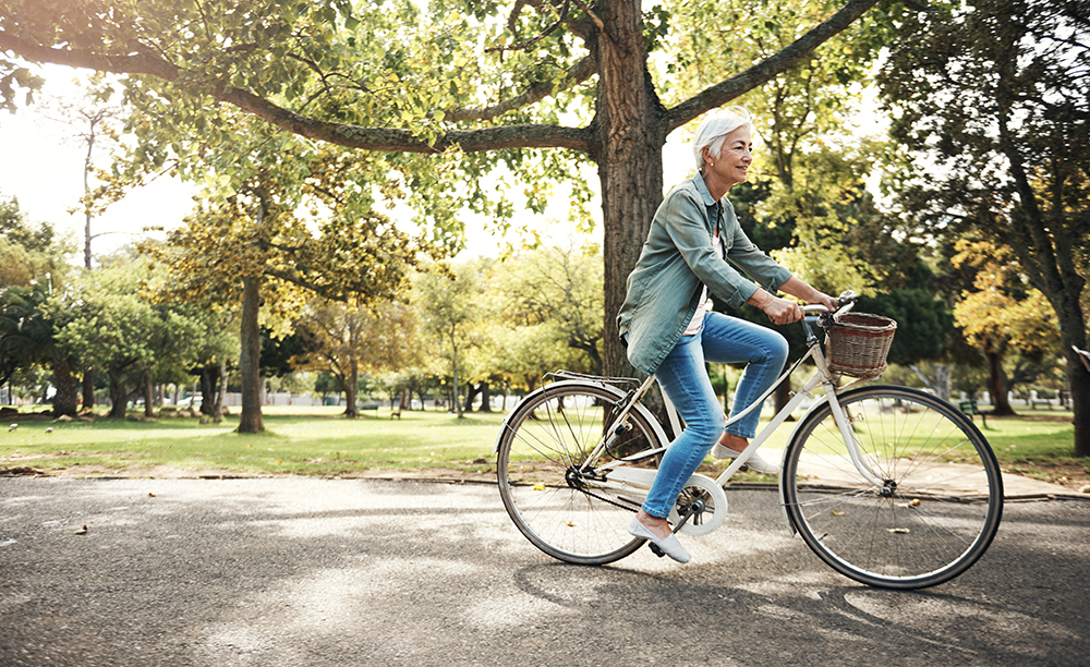 Una mujer mayor se mueve en bicicleta por un parque