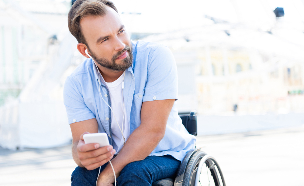 Un j&oacute;ven en silla de ruedas utiliza su tel&eacute;fono m&oacute;vil
