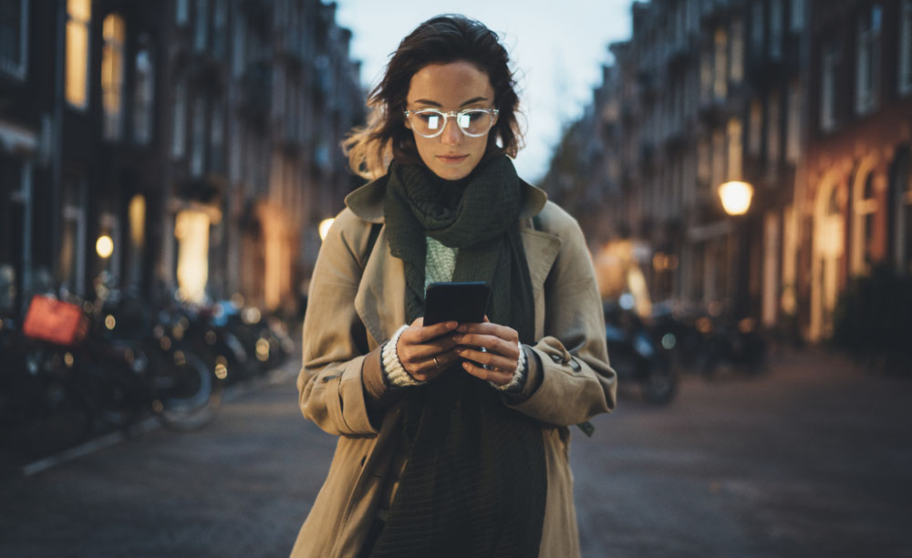 Una mujer utiliza su smartphone en una calle de noche