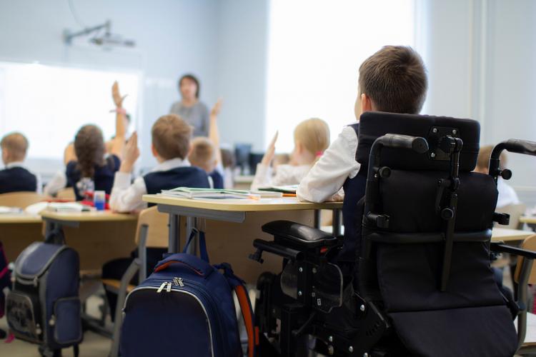 Fotografía de un aula con una niño en silla de ruedas en primer plano