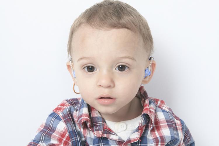 Un bebé con ayudas a la audición en los oídos