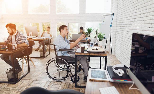 Fotografía de una oficina con un trabajador utilizando silla de ruedas
