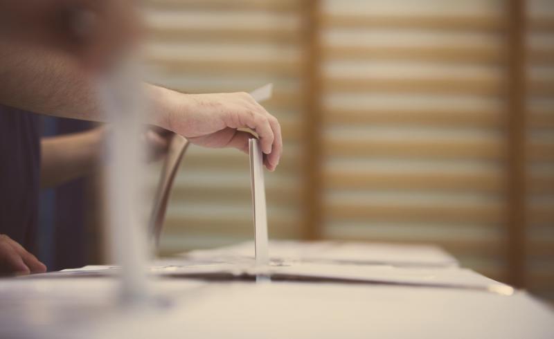 Una persona introduce su voto en una urna en unas elecciones.