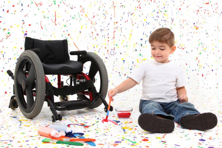 Un niño con espina bífida pinta en suelos y paredes al lado de una silla de ruedas