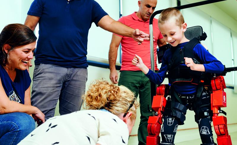 Un niño utiliza el exoesqueleto Atlas 2020 mientras es ayudado por profesionales