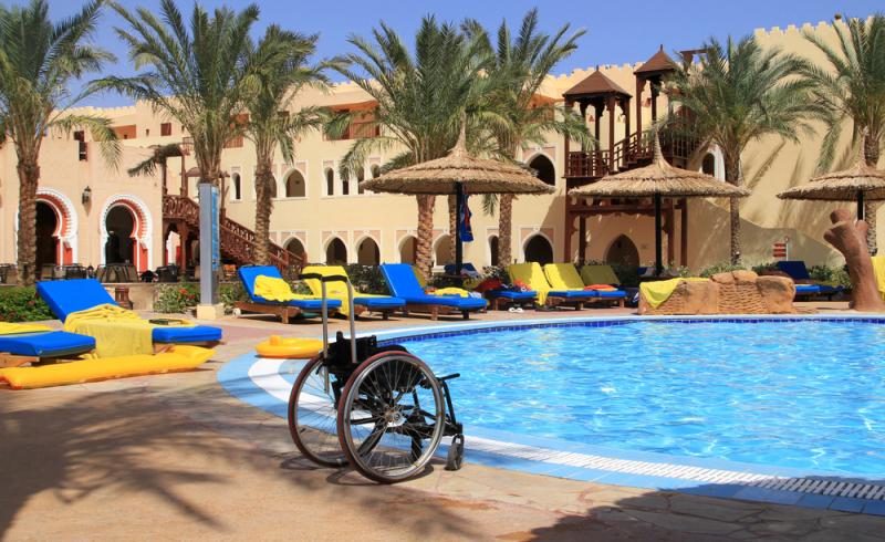 Fotografía de una silla de ruedas vacía en la zona de piscina de un hotel